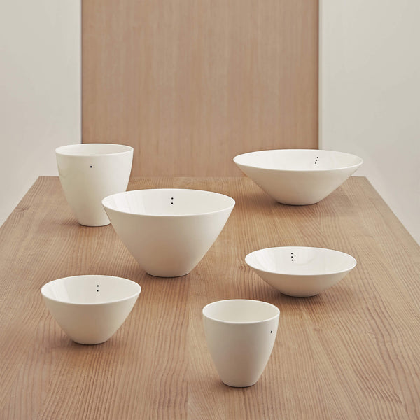 Collection of six porcelain bowls, in varying shapes and sizes, placed on a wooden table