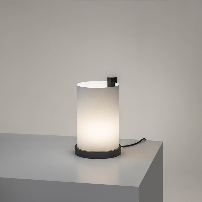Small table lamp with light on, and a black frame