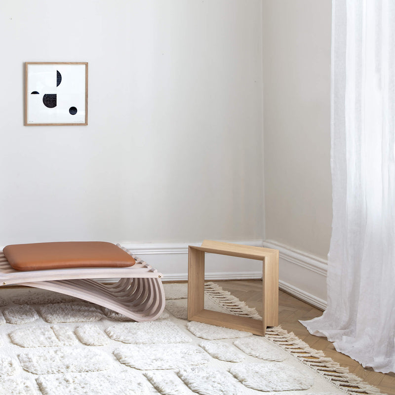 Light brown oak stool placed in a home, on a white carpet