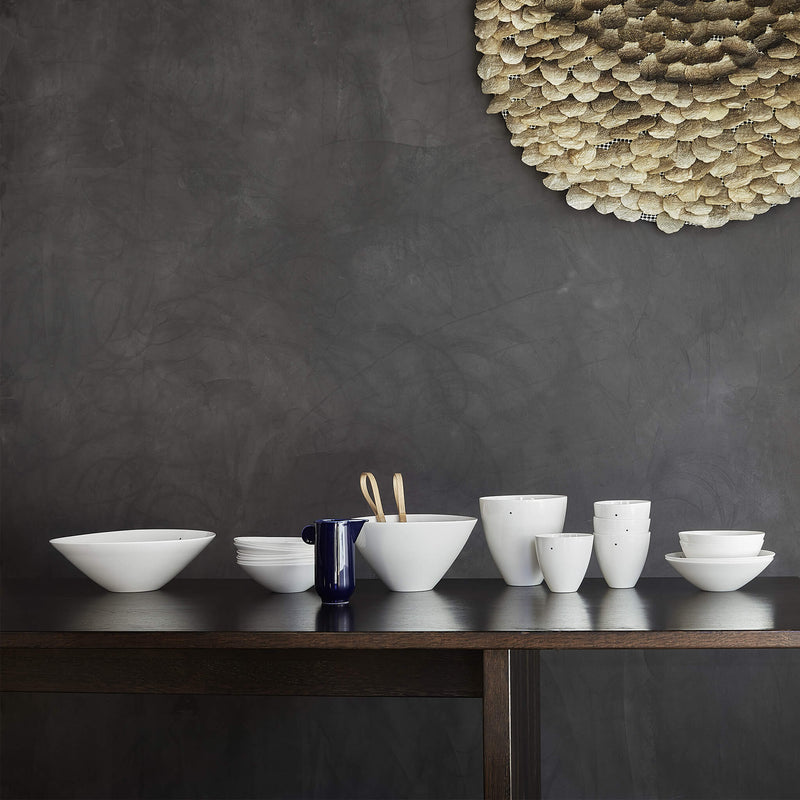 Collection of porcelain bowls in different shapes and sizes, displayed on a dark wooden table