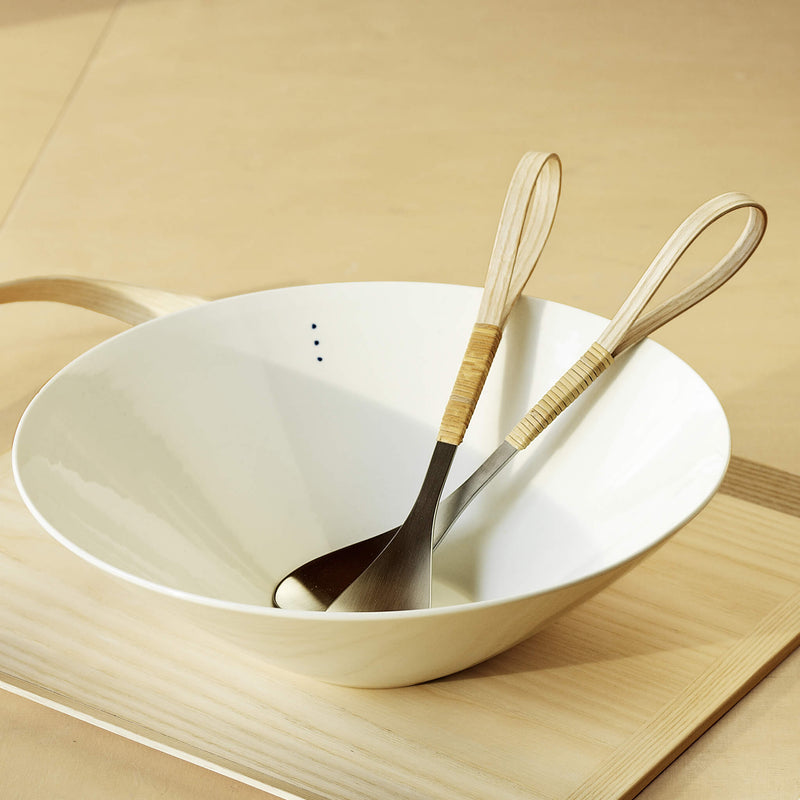 Porcelain bowl holding salad cutlery, placed on a wooden tray