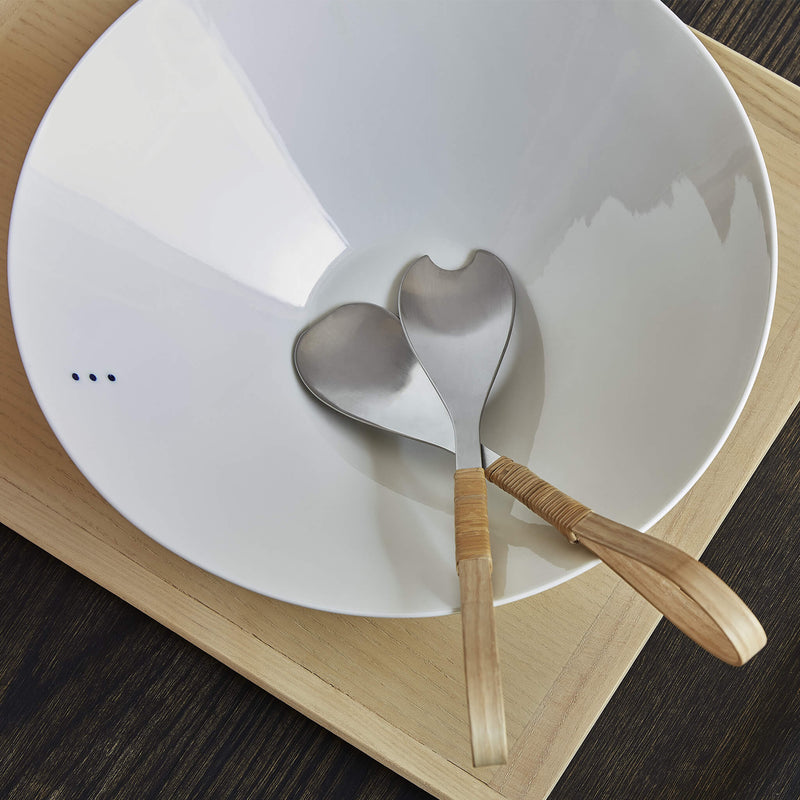 Top view of a porcelain bowl containing salad cutlery