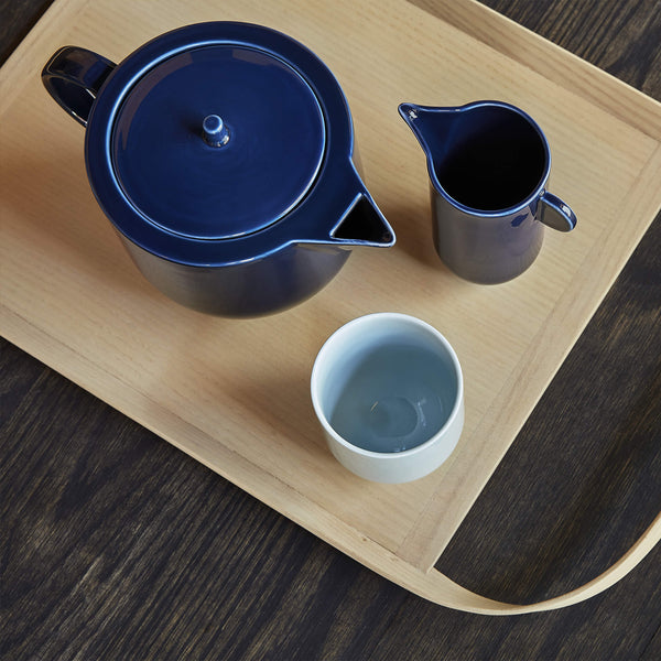 Porcelain tea set in blue tones, arranged on a wooden tray, top view