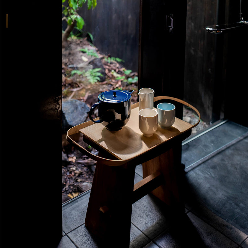 Porcelain tea set placed on a wooden tray, by a glass door
