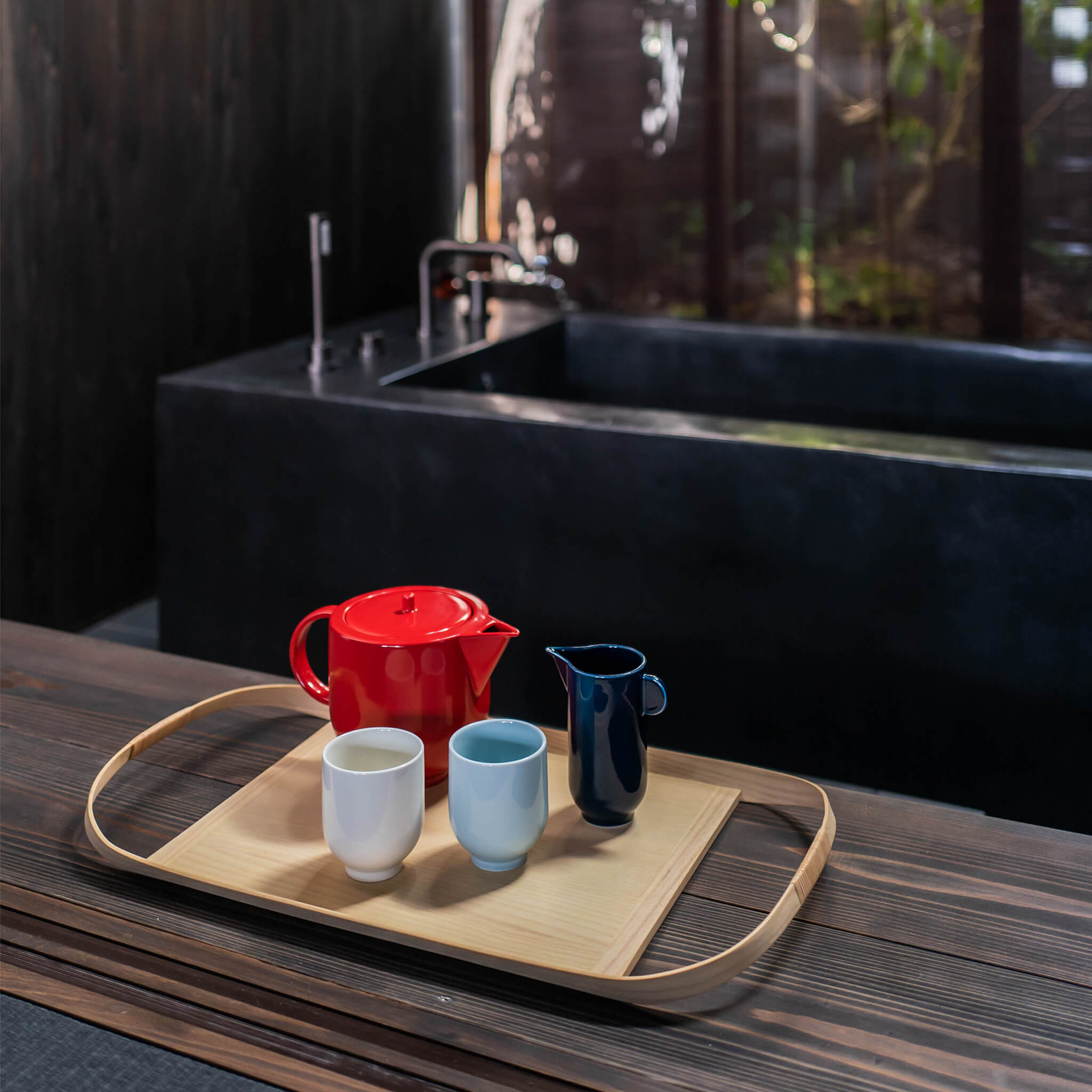 Wooden tray placed next to a bathtub, holding a tea set