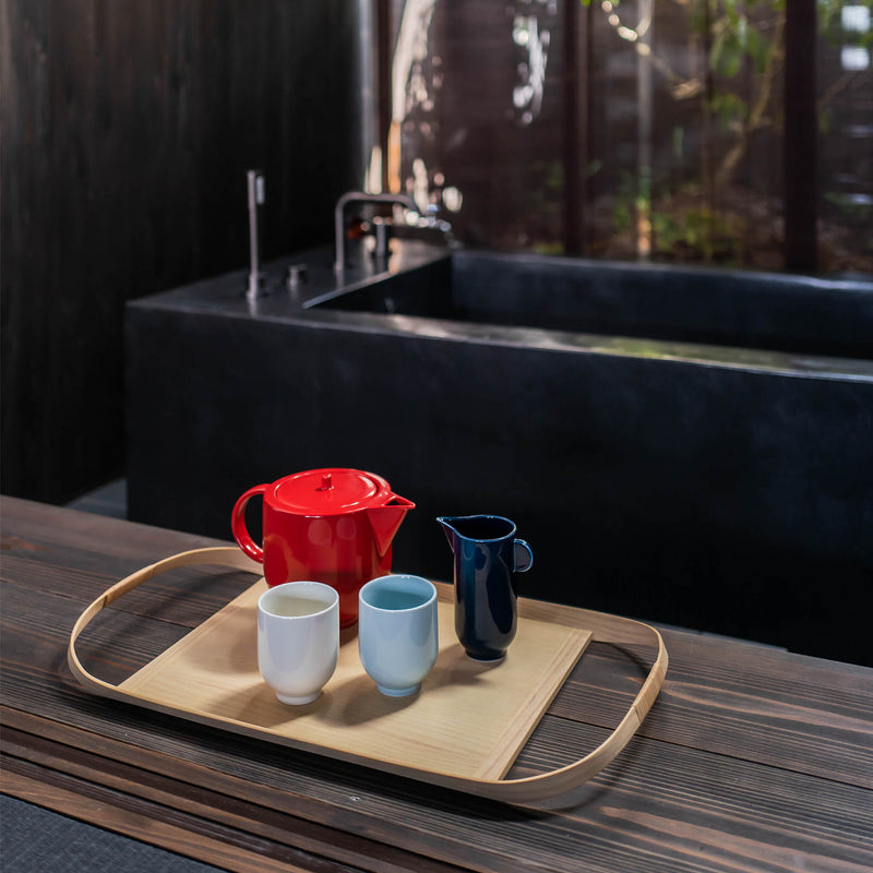 Wooden tray placed next to a bathtub, holding a tea set