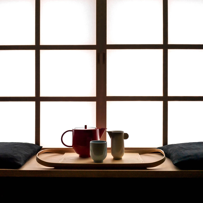 Porcelain tea set arranged on a wooden tray in a dark room