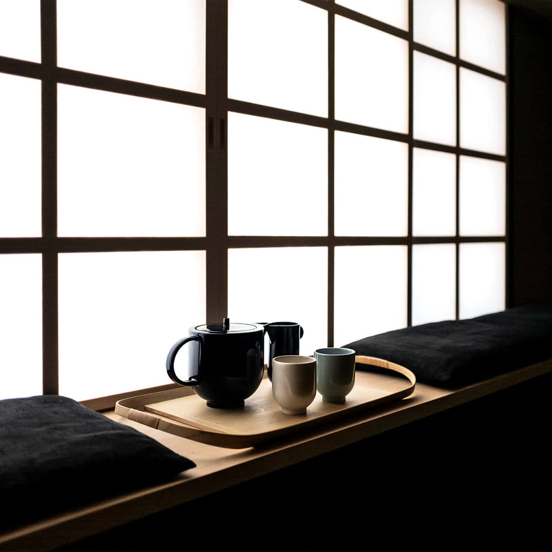 Wooden tray holding a tea set, placed by the window , in dim lighting