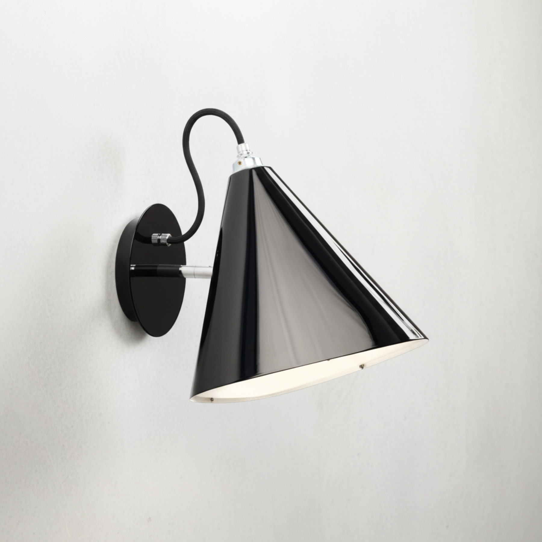 Wall sconce in glossy black with light grey mottled background